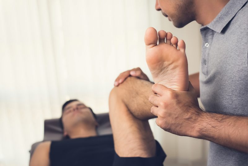 Therapist stretching athlete male patient in clinic - sport physical therapy concept