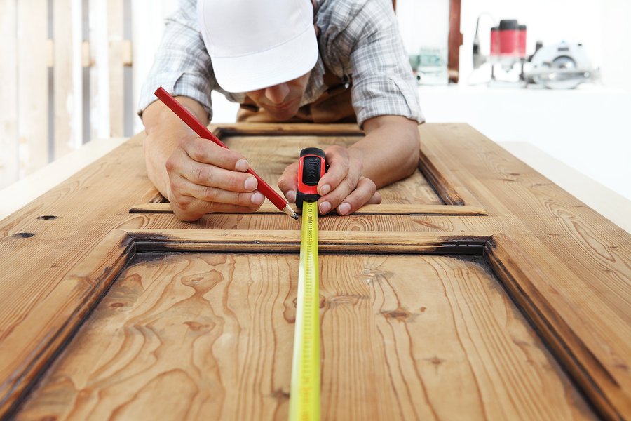 carpenter at work measures with the tape measure and pencil on wood background