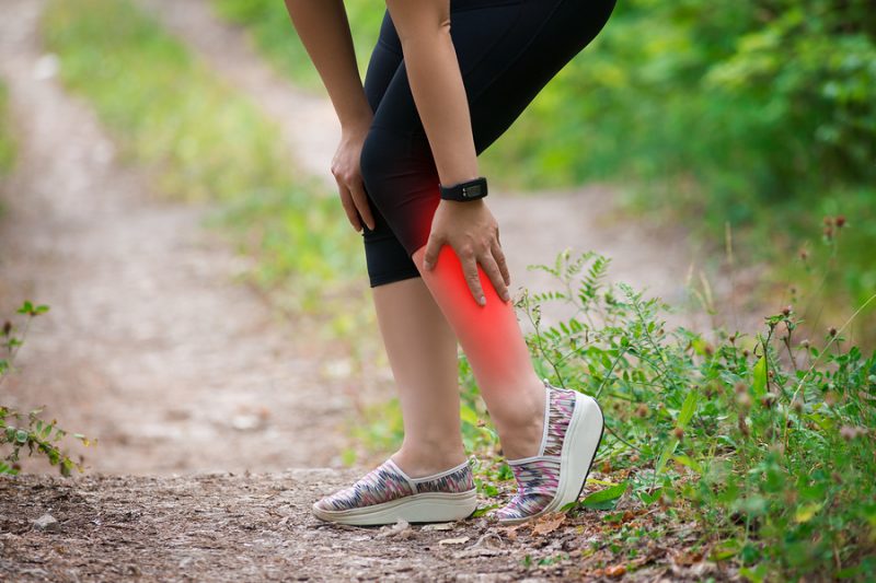 Pain in woman's shin, massage of female leg, injury while running, trauma during workout, outdoors concept